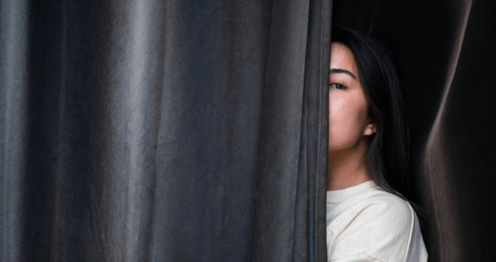 Woman hiding behind curtain