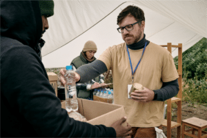 Volunteer giving water to a homeless man